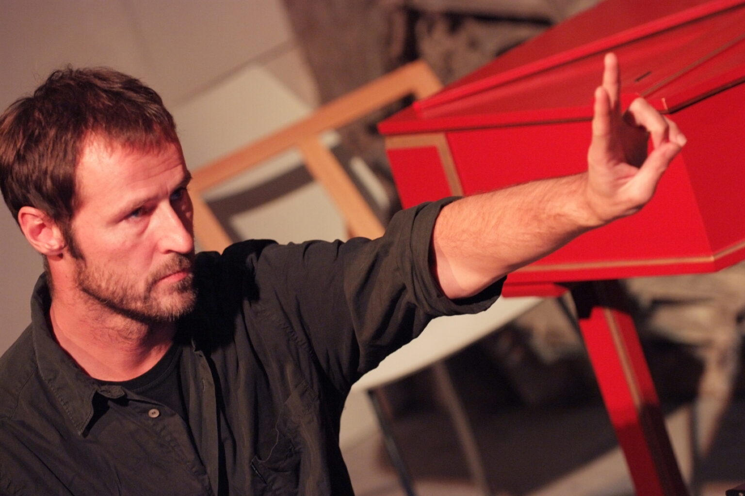 Michele Tadini beside a harpsichord, his arm raised in a musical gesture.